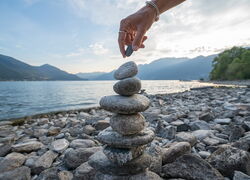Turm aus Steinen vor See, Bergpanorama