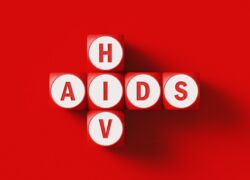 Holzwürfel mit Aufschrift HIV und AIDS auf rotem Untergrund