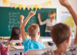 Zwei Schüler und eine Schülerin melden sich in der Klasse, die Lehrerin steht an der Tafel