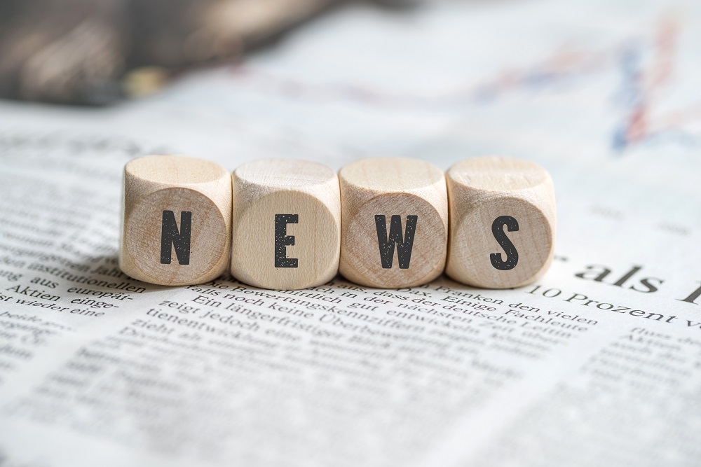 Holzwürfel mit dem Wort "News" auf einer Zeitung